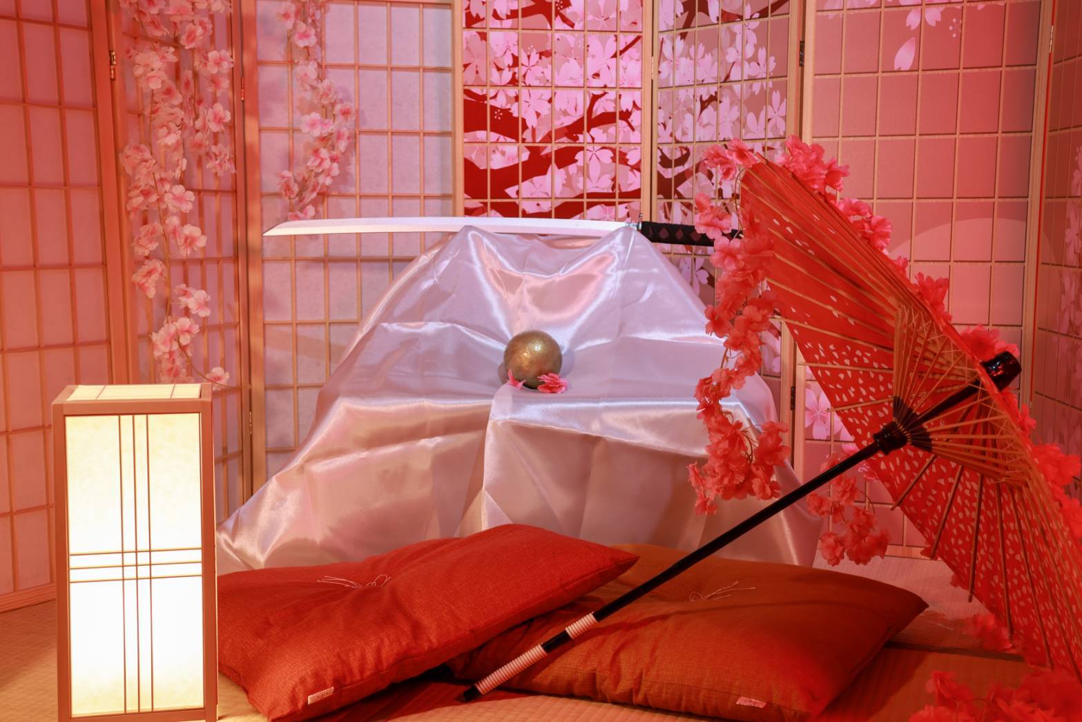 桜色のライティングに染まる和室 — 和傘と刀、座布団